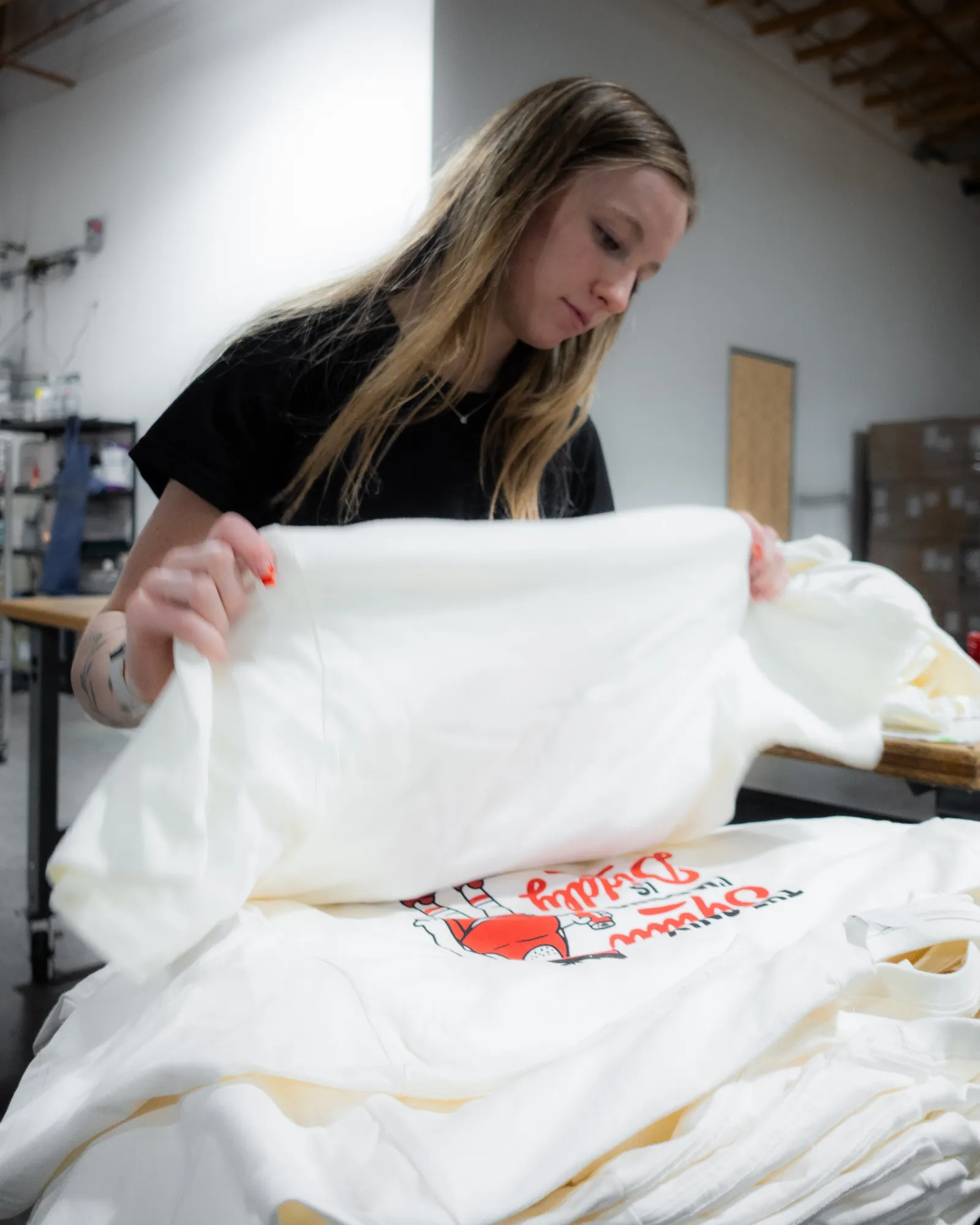 A shop worker folding freshly printed branded t-shirts