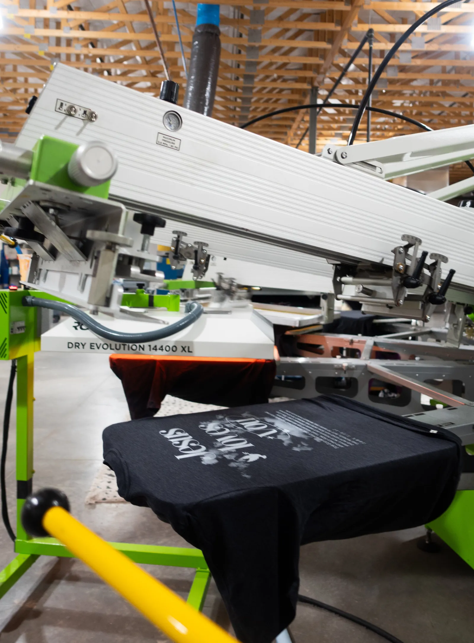 A garment on an automatic screen printing press in the Heart & Hook shop