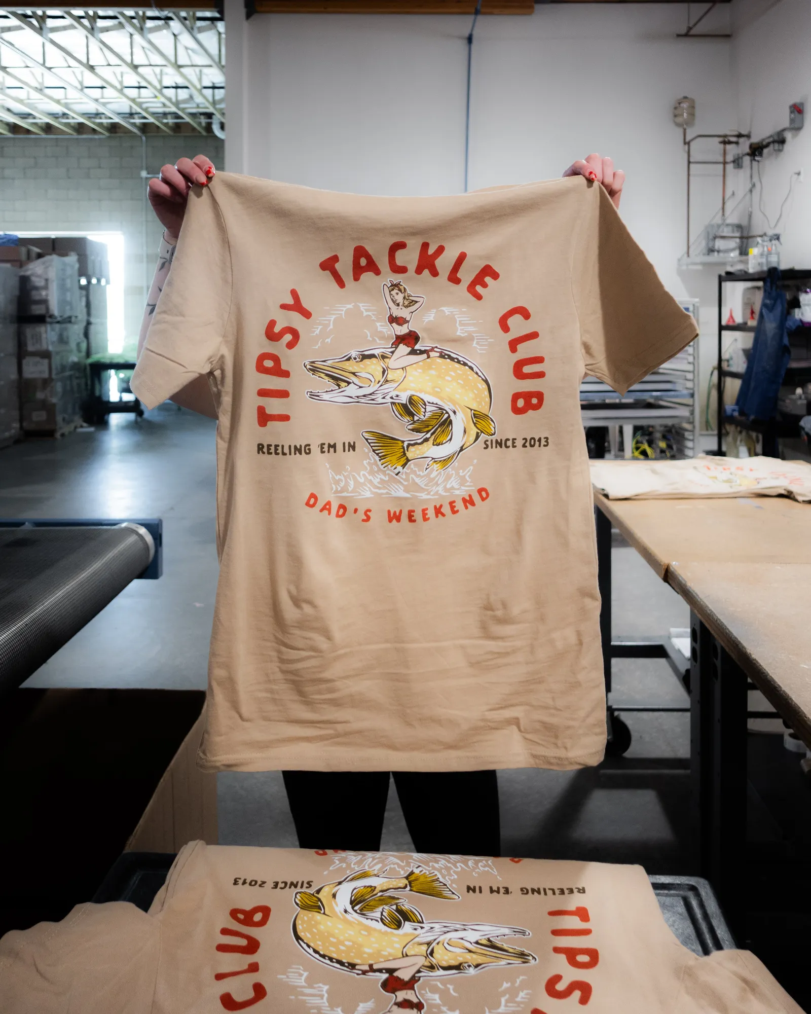 A custom screen-printed branded t-shirt held up in the shop